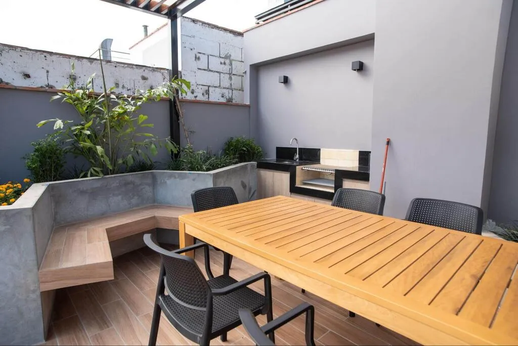 varanda gourmet de apartamento com plantas e mesa de madeira com cadeiras